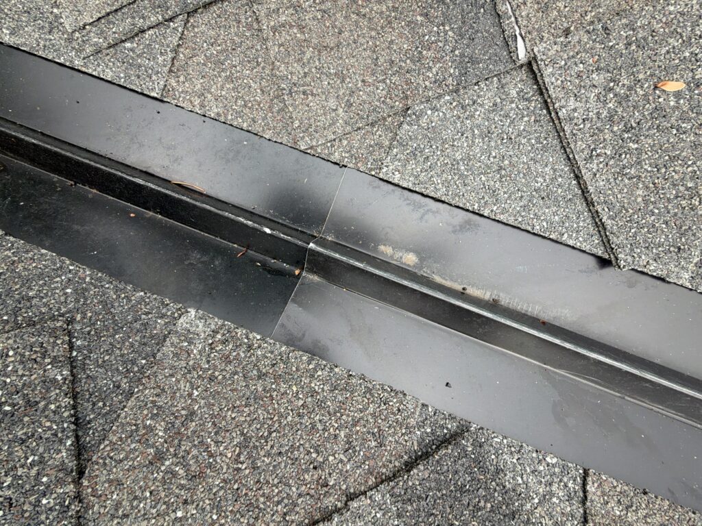 Close-up of metal valley flashing between asphalt-shingle roof slopes