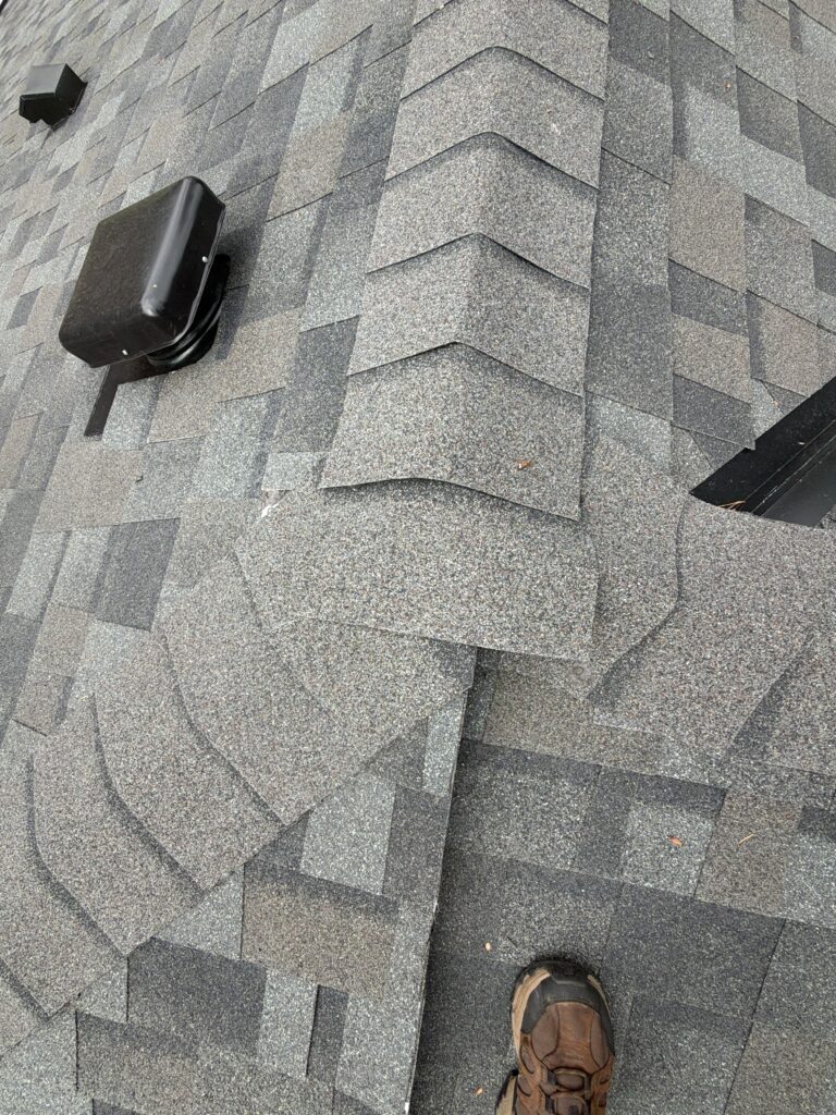 Ridge cap shingles beside a black roof vent