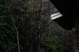 Rainwater falling from the edge of a residential roof.