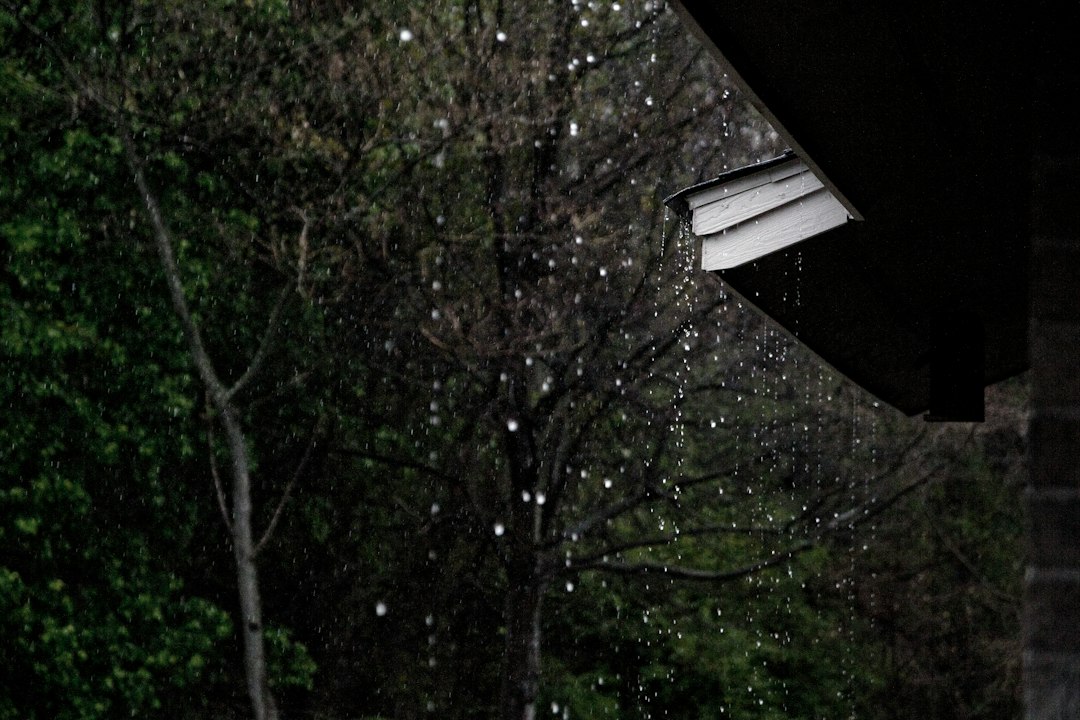 Rainwater falling from the edge of a residential roof.
